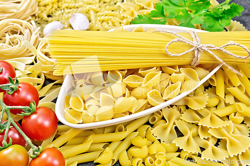 Image of Pasta different with bowl and tomatoes on dark board