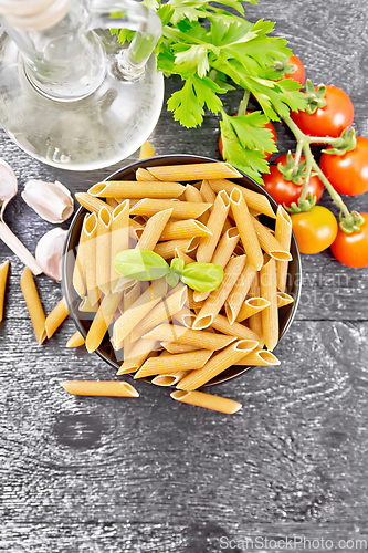 Image of Penne whole grain in bowl with vegetables on dark board top