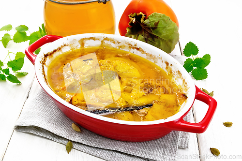 Image of Persimmons baked with honey in pan on wooden board