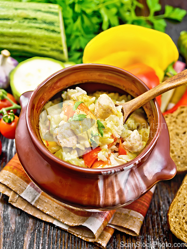 Image of Rice with chicken and vegetables in pot on brown board