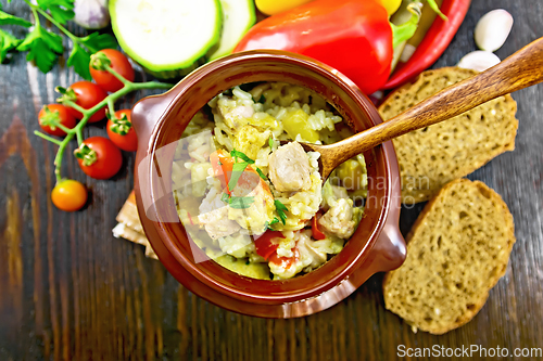 Image of Rice with chicken and vegetables in pot on dark board top