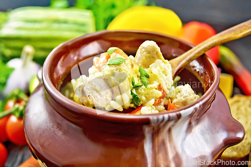 Image of Rice with chicken and vegetables in pot on dark board