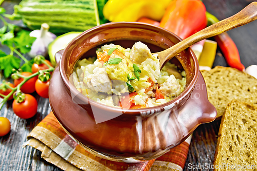 Image of Rice with chicken and vegetables in pot on wooden board