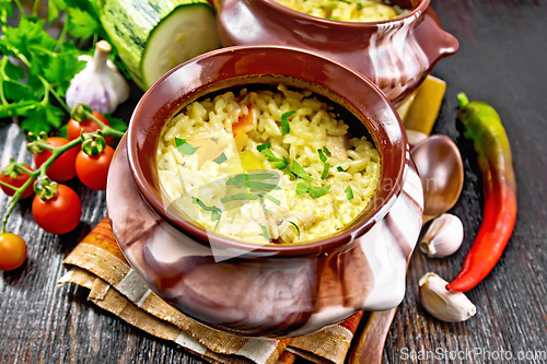 Image of Rice with chicken and vegetables in two pots on dark board