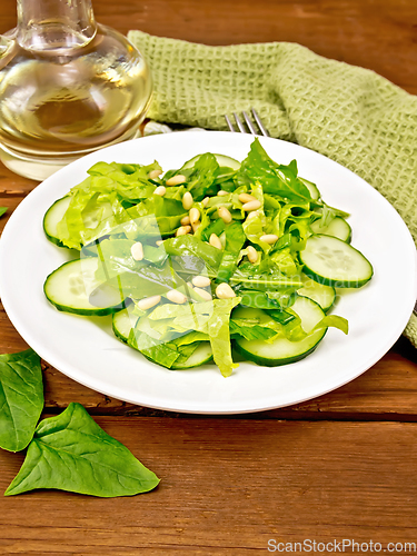 Image of Salad from spinach and cucumbers with napkin on table