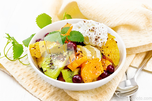 Image of Salad fruit with cranberries and cream in bowl on board