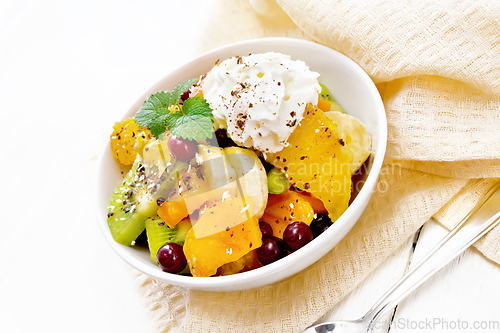 Image of Salad fruit with cranberries and cream in bowl on light board