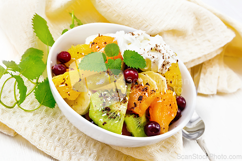 Image of Salad fruit with cranberries and cream in bowl on wooden board