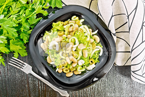 Image of Salad of beans and olives in plate on board top