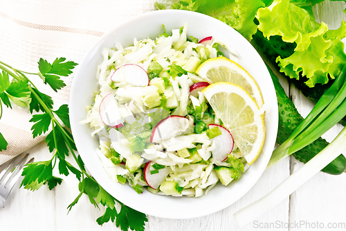 Image of Salad of cabbage with radish in plate on board top