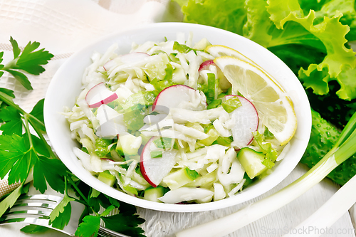 Image of Salad of cabbage with radish in plate on wooden board