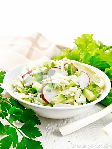 Image of Salad of cabbage with radish in plate on wooden table