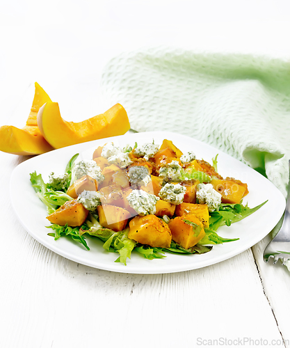 Image of Salad of pumpkin and cheese in plate on light wooden board