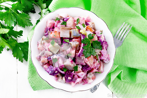 Image of Salad with herring and beetroot in bowl on board top