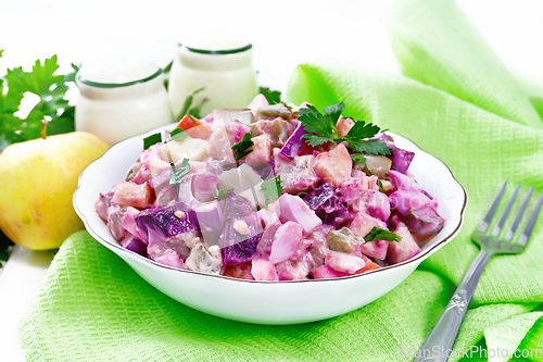 Image of Salad with herring and beetroot in bowl on board