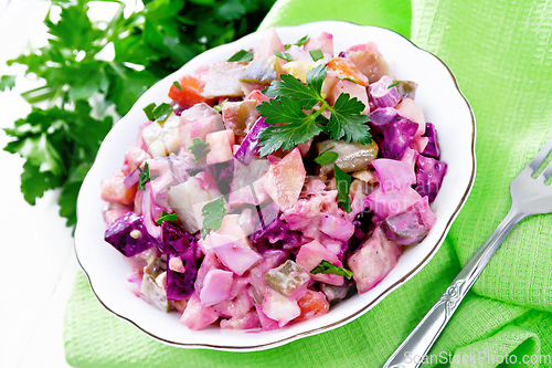 Image of Salad with herring and beetroot in bowl on light board