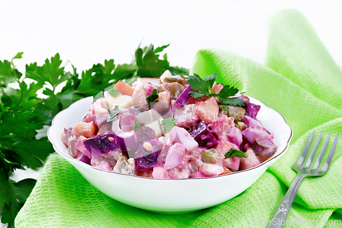 Image of Salad with herring and beetroot in bowl on wooden board