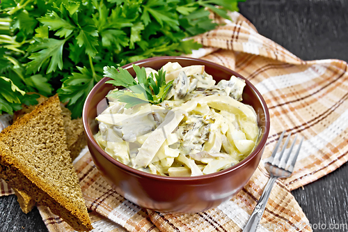 Image of Salad with squid and champignons in bowl on dark board