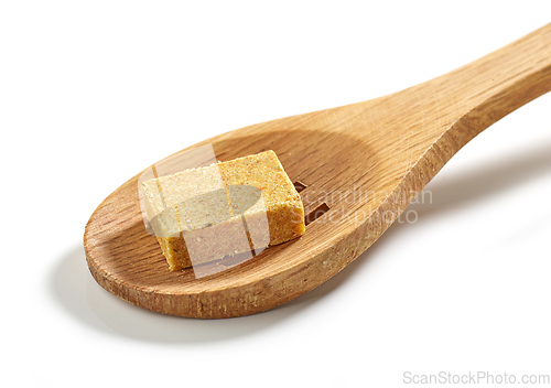 Image of instant chicken broth cube in wooden spoon