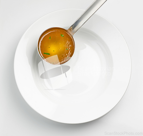 Image of empty white soup plate and broth ladle 