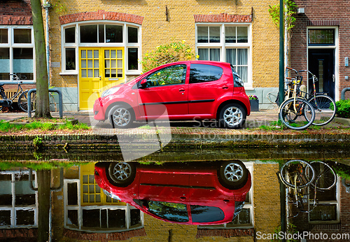 Image of Red car on canal embankment in street of Delft. Delft, Netherlands