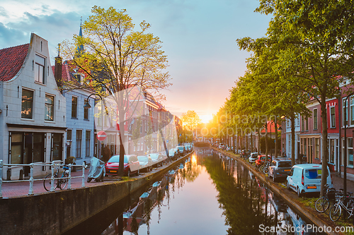 Image of Delt canal with old houses and cars parked along on sunset