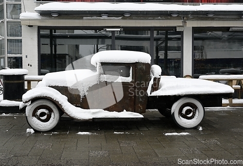 Image of old rusty retro car covered with snow