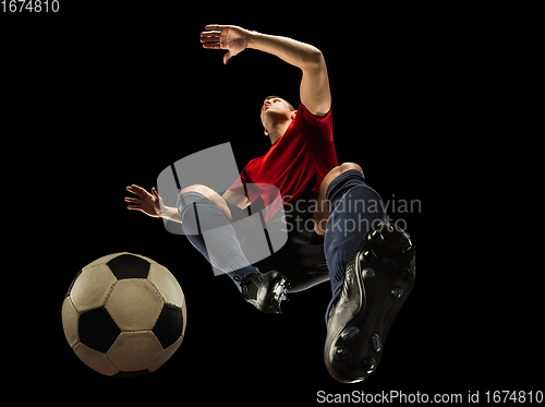 Image of Young caucasian football, soccer player in action, motion isolated on black background, look from the bottom. Concept of sport, movement, energy and dynamic.