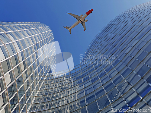Image of Plane flying over modern office glass skyscrapers