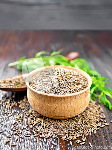 Image of Cumin seeds in bowl and spoon with herbs on table