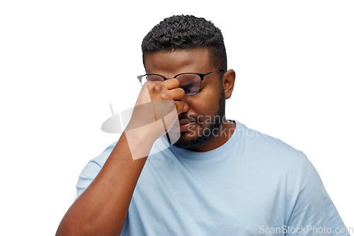 Image of tired african man in lasses touching nose bridge