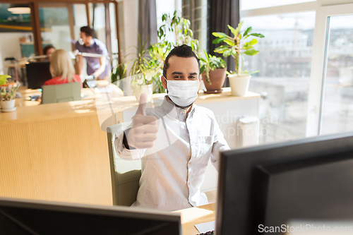 Image of male office worker in mask showing thumbs up