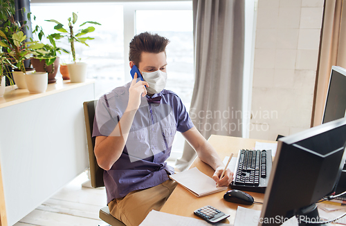 Image of male office worker in mask calling on smarphone