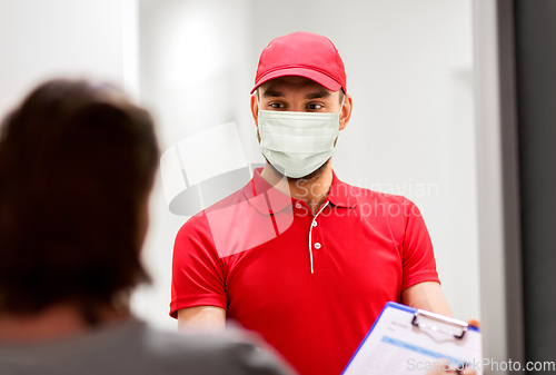 Image of delivery man in mask and customer signing papers