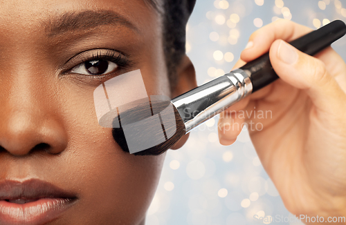 Image of face of african woman and hand with make up brush