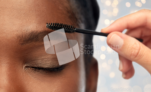 Image of face of african woman and hand with mascara brush