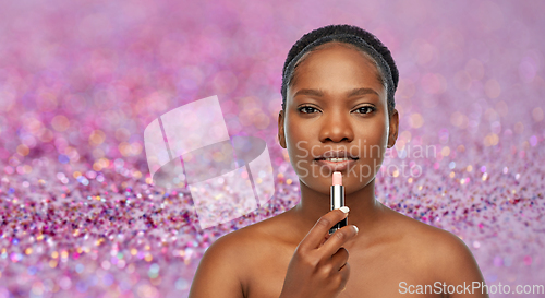 Image of african american woman applying lipstick