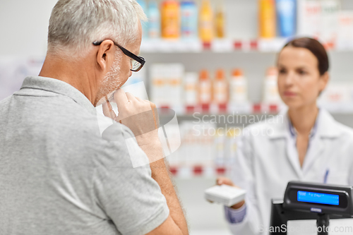 Image of pharmacist and old man with medicine at pharmacy