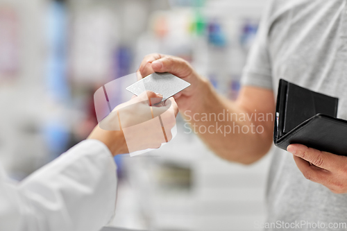 Image of close up of hand giving bank card to pharmacist