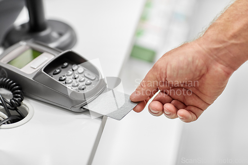 Image of close up of hand with credit card in card-reader