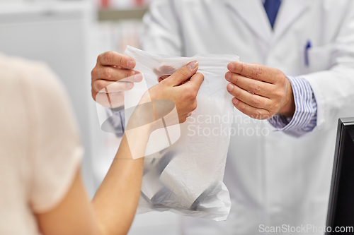 Image of senior apothecary and woman with drug at pharmacy