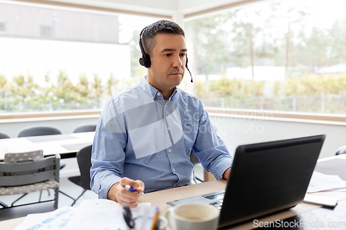 Image of man with headset and laptop working at home