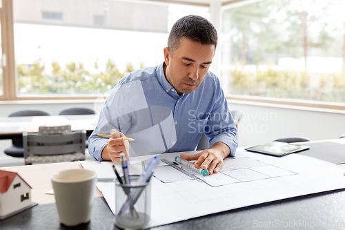 Image of architect with blueprint working at home office