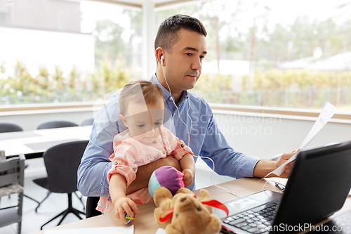 Image of father with baby and papers working at home office