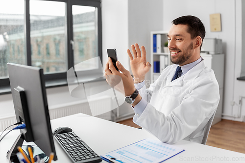 Image of doctor with smartphone having video call at clinic