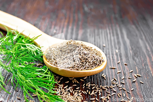 Image of Cumin seeds in spoon with herbs on wooden table