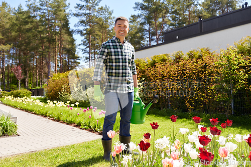 Image of happy man with watering can and flowers at garden