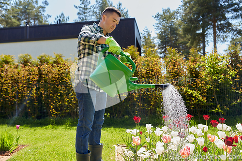 Image of middle-aged man watering flowers at garden