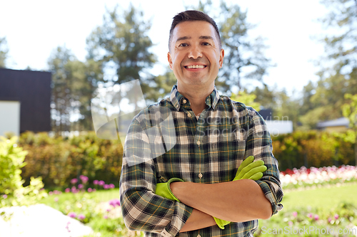 Image of happy smiling middle-aged man in gloves at garden