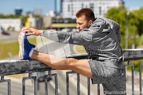 Image of man stretching leg on bridge
